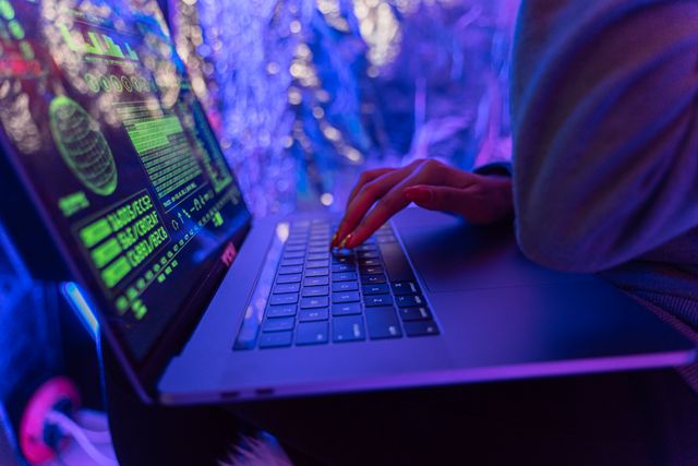 Close-up of hands typing on a laptop showing a compromised website with security warnings on screen